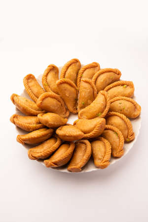 Gujiya or gujia or karanji - sweet dumplings made during the festival of holi and diwali, served in a plate. selective focusの写真素材