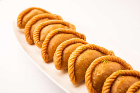 Gujiya or gujia or karanji - sweet dumplings made during the festival of holi and diwali, served in a plate. selective focusの写真素材