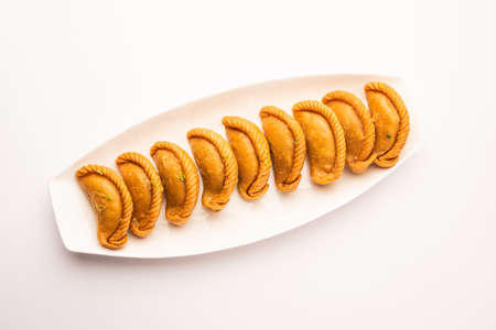 Gujiya or gujia or karanji - sweet dumplings made during the festival of holi and diwali, served in a plate. selective focusの写真素材