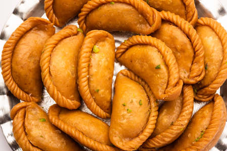 Gujiya or gujia or karanji - sweet dumplings made during the festival of holi and diwali, served in a plate. selective focusの写真素材