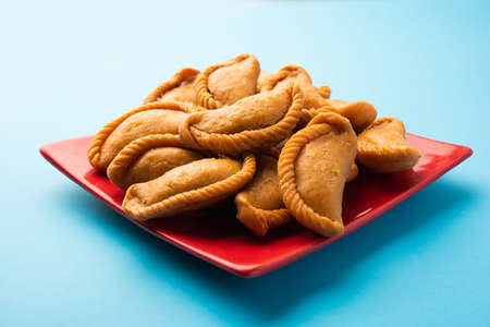 Gujiya or gujia or karanji - sweet dumplings made during the festival of holi and diwali, served in a plate. selective focusの写真素材