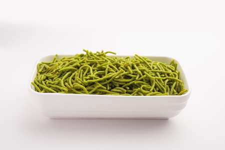 Spinach or palak sev are crunchy fried savory noodles. Homemade Thick and thin greenÂ shev or namkeen is a classic Indian snack. served in a bowl or plateの写真素材