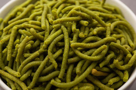 Spinach or palak sev are crunchy fried savory noodles. Homemade Thick and thin greenÂ shev or namkeen is a classic Indian snack. served in a bowl or plateの写真素材