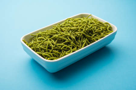 Spinach or palak sev are crunchy fried savory noodles. Homemade Thick and thin greenÂ shev or namkeen is a classic Indian snack. served in a bowl or plateの写真素材