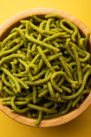 Spinach or palak sev are crunchy fried savory noodles. Homemade Thick and thin greenÂ shev or namkeen is a classic Indian snack. served in a bowl or plateの写真素材
