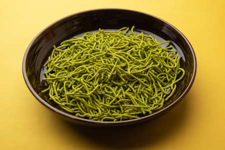 Spinach or palak sev are crunchy fried savory noodles. Homemade Thick and thin greenÂ shev or namkeen is a classic Indian snack. served in a bowl or plateの写真素材