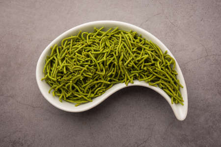 Spinach or palak sev are crunchy fried savory noodles. Homemade Thick and thin greenÂ shev or namkeen is a classic Indian snack. served in a bowl or plateの写真素材