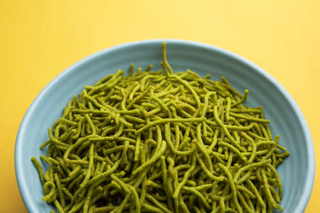 Spinach or palak sev are crunchy fried savory noodles. Homemade Thick and thin greenÂ shev or namkeen is a classic Indian snack. served in a bowl or plateの写真素材