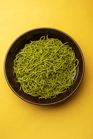 Spinach or palak sev are crunchy fried savory noodles. Homemade Thick and thin greenÂ shev or namkeen is a classic Indian snack. served in a bowl or plateの写真素材