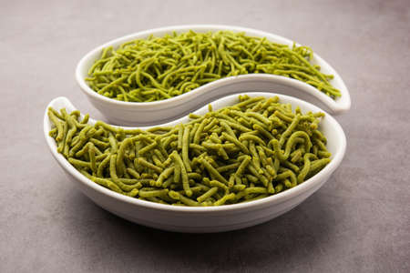 Spinach or palak sev are crunchy fried savory noodles. Homemade Thick and thin greenÂ shev or namkeen is a classic Indian snack. served in a bowl or plateの写真素材