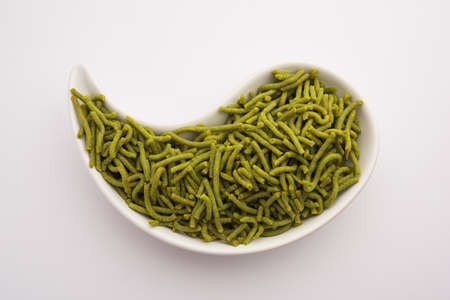 Spinach or palak sev are crunchy fried savory noodles. Homemade Thick and thin greenÂ shev or namkeen is a classic Indian snack. served in a bowl or plateの写真素材
