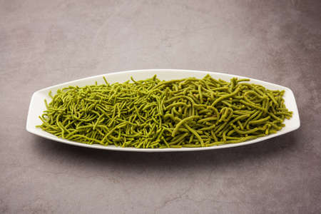 Spinach or palak sev are crunchy fried savory noodles. Homemade Thick and thin greenÂ shev or namkeen is a classic Indian snack. served in a bowl or plateの写真素材