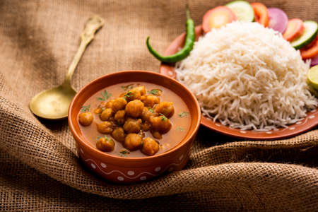 Indian food chole chawal or spicy Chickpea curry with plain rice served with green salad. selective...