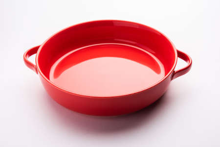 Empty red ceramic serving bowl, isolated over white or gray backgroundの写真素材