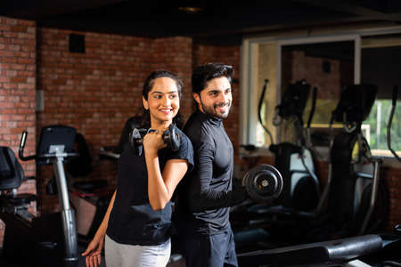 Indian asian Young couple is working out in the gym. Attractive woman and handsome fit man are...