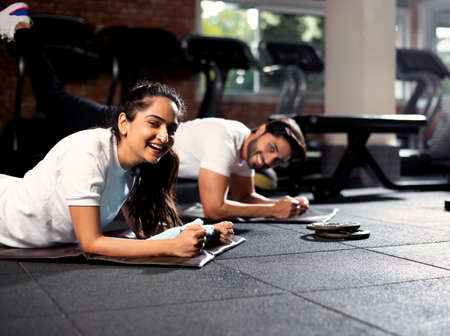 Indian sporty young couple doing plank exercise in gym for abs or core, selective focusの写真素材
