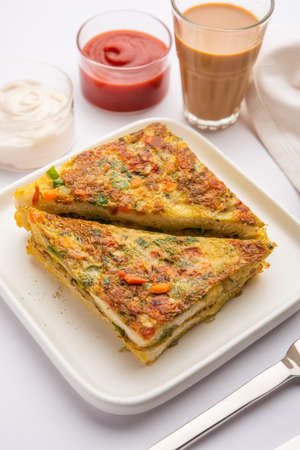 Bread Omelette is a quick and easy breakfast from India. Fresh bread slices dipped into egg batter with spices and shallow fried. served with tomato ketchup and teaの写真素材