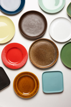 Empty colourful ceramic plates in group over white background, top viewの写真素材