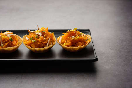 Carrot or Gajar Halwa canape or canapÃ© or Fusion Tart, garnished with dry fruits. Indian dessert