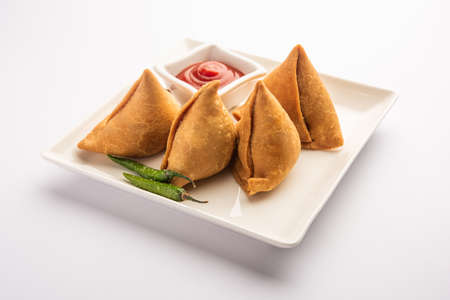 Veg Samosa - is a crispy and spicy Indian triangle shape snack which has crisp outer layer of maida & filling of mashed potato, peas and spicesの写真素材