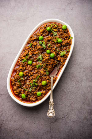 Mutton Kheema Pav OR Indian Spicy Minced Meat served with bread OR kulcha, garnished with green peas. Moody background. Selective focusの写真素材