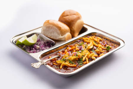 Misal pav is a popular Maharashtrian street food of usal, sprouts curry, topped with onions, tomatoes, farsan and chutneyの写真素材