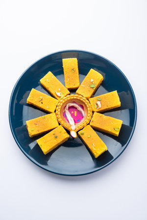 Mysore Pak and diwali diya or clay lamp decorated in a plate - Happy Diwali Greetingの写真素材