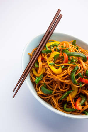 Schezwan Noodles or Szechwan vegetable Hakka Noodles or chow mein is a popular Indo-Chinese recipes, served in a bowl or plate with wooden chopsticksの写真素材