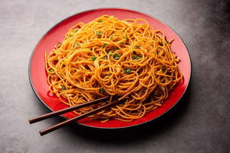 Schezwan Noodles or Szechwan vegetable Hakka Noodles or chow mein is a popular Indo-Chinese recipes, served in a bowl or plate with wooden chopsticksの写真素材