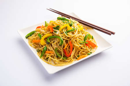 Schezwan Noodles or Szechwan vegetable Hakka Noodles or chow mein is a popular Indo-Chinese recipes, served in a bowl or plate with wooden chopsticksの写真素材