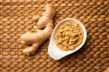 Fresh mashed ginger paste or Puree in a bowl and whole Adrak over moody background, selective focusの写真素材
