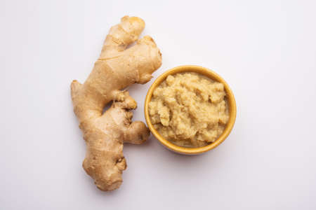 Fresh mashed ginger paste or Puree in a bowl and whole Adrak over moody background, selective focusの写真素材