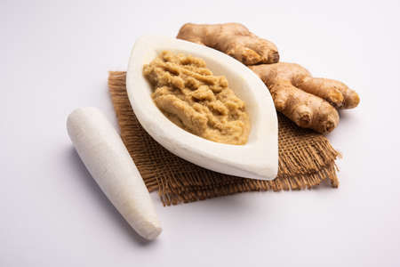 Fresh mashed ginger paste or Puree in a bowl and whole Adrak over moody background, selective focusの写真素材