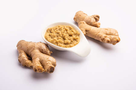 Fresh mashed ginger paste or Puree in a bowl and whole Adrak over moody background, selective focusの写真素材