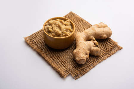 Fresh mashed ginger paste or Puree in a bowl and whole Adrak over moody background, selective focusの写真素材