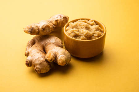 Fresh mashed ginger paste or Puree in a bowl and whole Adrak over moody background, selective focusの写真素材