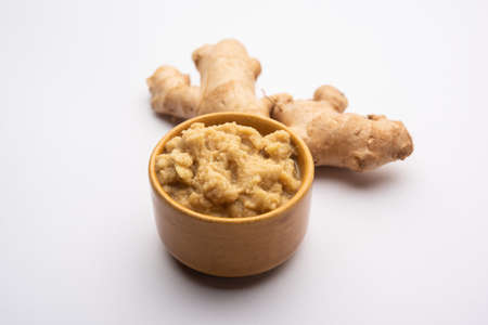 Fresh mashed ginger paste or Puree in a bowl and whole Adrak over moody background, selective focusの写真素材
