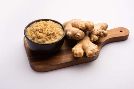 Fresh mashed ginger paste or Puree in a bowl and whole Adrak over moody background, selective focusの写真素材