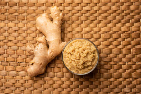 Fresh mashed ginger paste or Puree in a bowl and whole Adrak over moody background, selective focusの写真素材