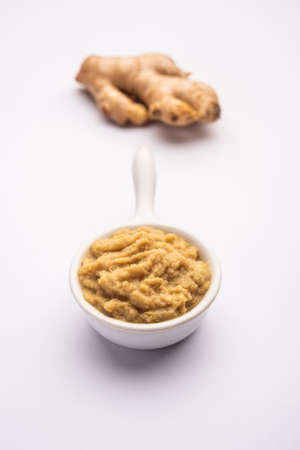 Fresh mashed ginger paste or Puree in a bowl and whole Adrak over moody background, selective focusの写真素材
