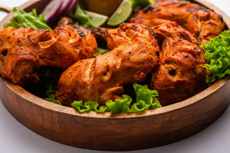 Tandoori chicken is a chicken dish prepared by roasting chicken marinated in yogurt and spices in a tandoor or a clay oven, served with onion and green chutneyの写真素材