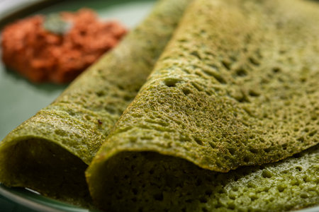 Palak dosa made using mixing spinach or keerai in batter, served with red chutney