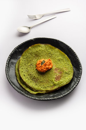 Palak dosa made using mixing spinach or keerai in batter, served with red chutneyの写真素材