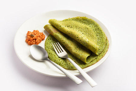 Palak dosa made using mixing spinach or keerai in batter, served with red chutneyの写真素材