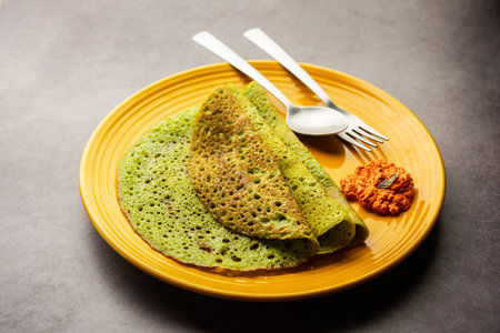Palak dosa made using mixing spinach or keerai in batter, served with red chutneyの写真素材