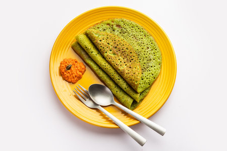 Palak dosa made using mixing spinach or keerai in batter, served with red chutneyの写真素材