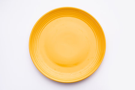 Empty Yellow ceramic plate isolated over white backgroundの写真素材