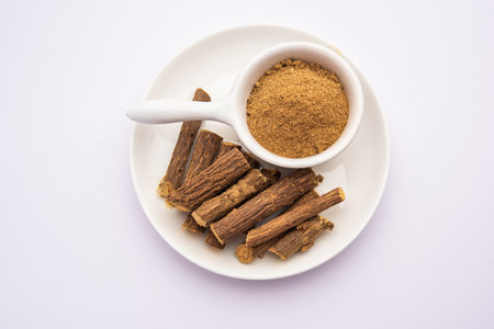 Ayurvedic Mulethi or Liquorice root stick or jeshthamadh powder served in a bowl over moody backgroundの写真素材