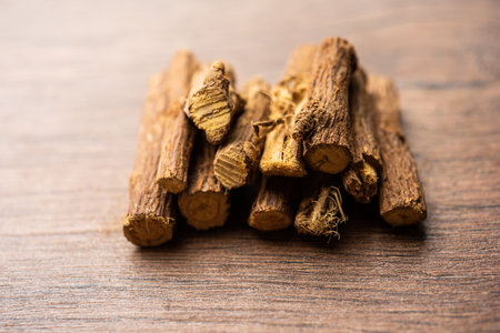 Ayurvedic Mulethi or Liquorice root stick or jeshthamadh powder served in a bowl over moody backgroundの写真素材