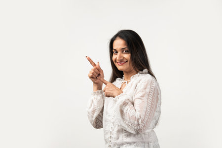 Beautiful mid age Asian woman pointing up to copy space and looking at camera with smileの写真素材